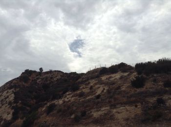 Low angle view of mountain against cloudy sky