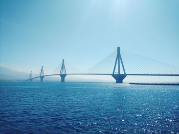 Suspension bridge over sea against clear blue sky