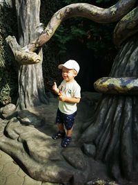 Full length of boy standing on tree trunk