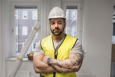 Portrait of young man standing against yellow wall