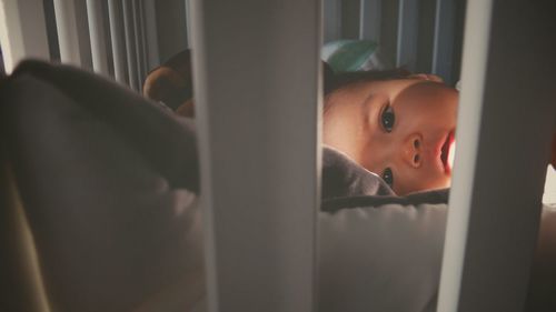 Close-up of baby girl on bed at home