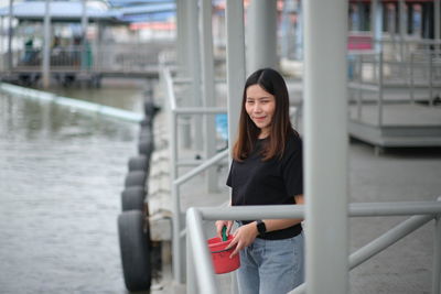 Portrait of beautiful woman standing by railing in canal