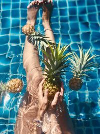 Low section of woman holding pineapple in swimming pool