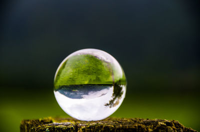 Close-up of crystal ball against sky