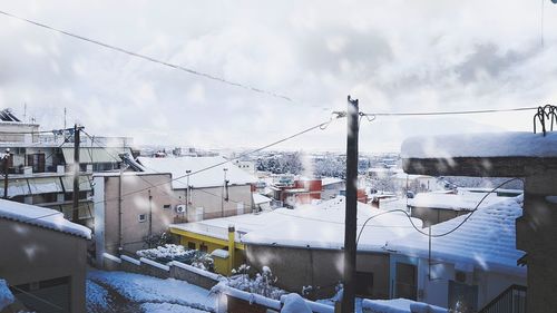 Snow covered houses and buildings in city against sky