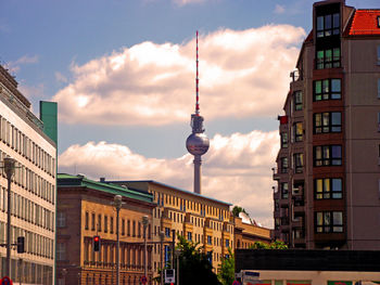 Fernsehturm and multi colored buildings against sky during sunset