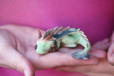 Midsection of woman holding dragon clay sculpture