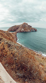 Scenic view of rocks on sea shore against sky