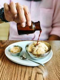 Close-up of hand holding ice cream on table