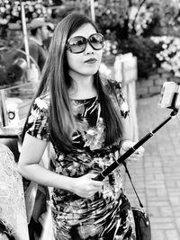 Woman wearing sunglasses holding monopod while standing outdoors