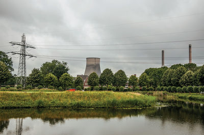 Reflection of trees and electricity pylon against sky