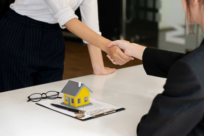 Midsection of business people shaking hands in office