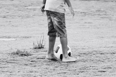 Low section of boy with soccer ball standing on field