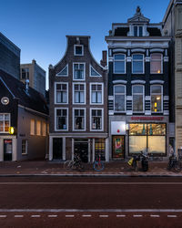 Street by buildings against sky at dusk