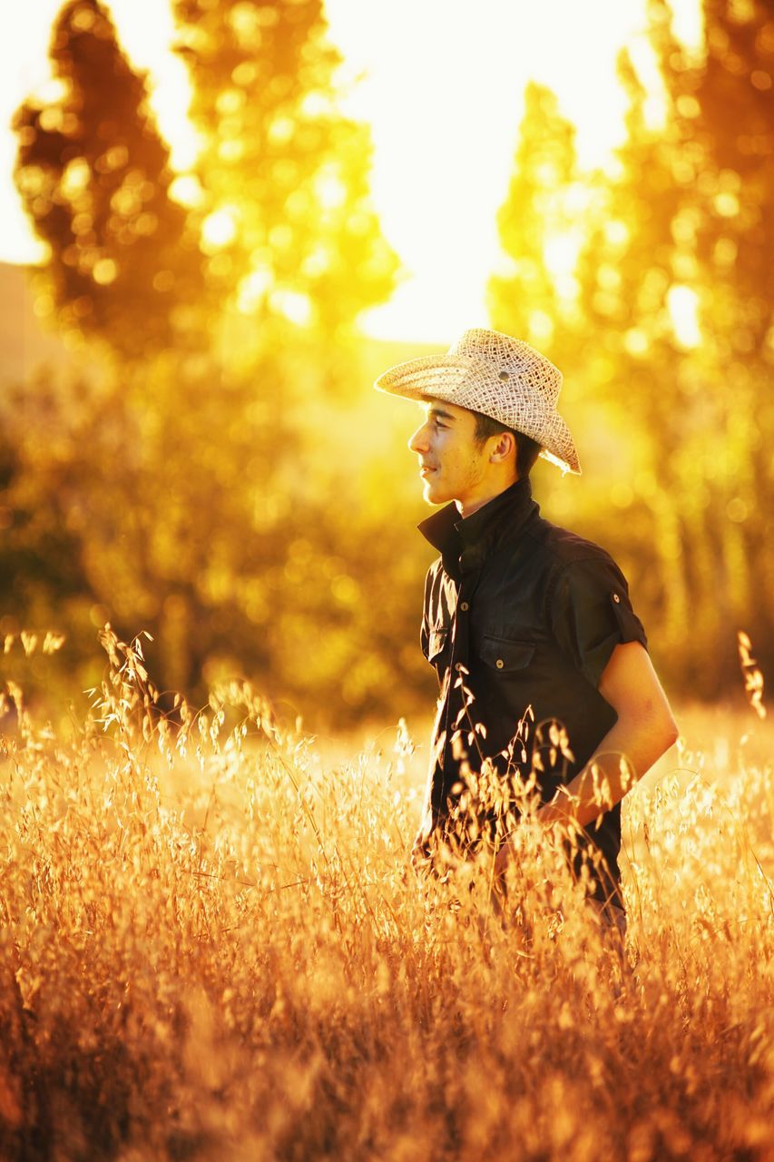 WOMAN WEARING HAT ON FIELD DURING SUNSET