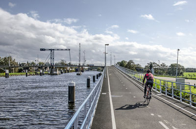 Man riding bicycle on road against sky