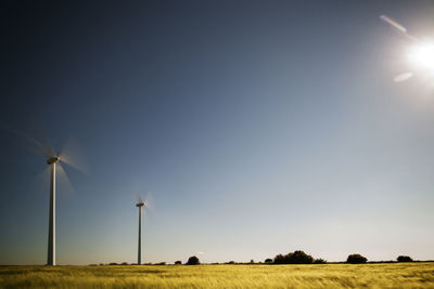 Wind turbines on field against clear sky