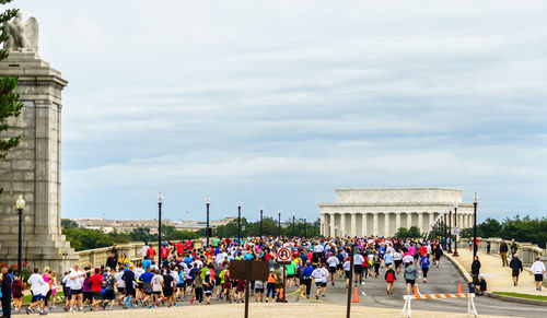 Rear view of people running in marathon against sky