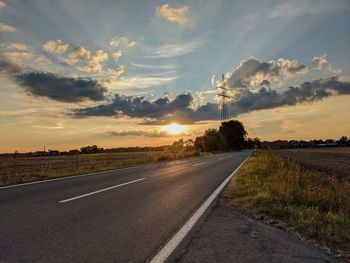 Empty road along landscape at sunset