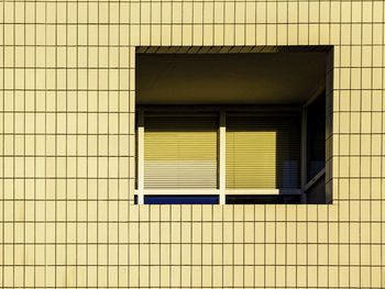 Full frame shot of building. window detail with a blind that has a faded portion.