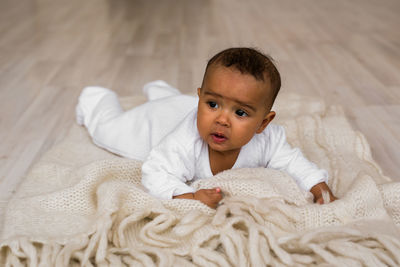 Portrait of cute baby lying on bed at home