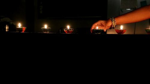 Close-up of hand holding lit candles