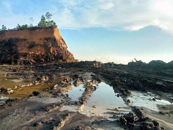 Rock formations on shore against sky