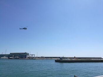 Airplane flying over sea against clear blue sky