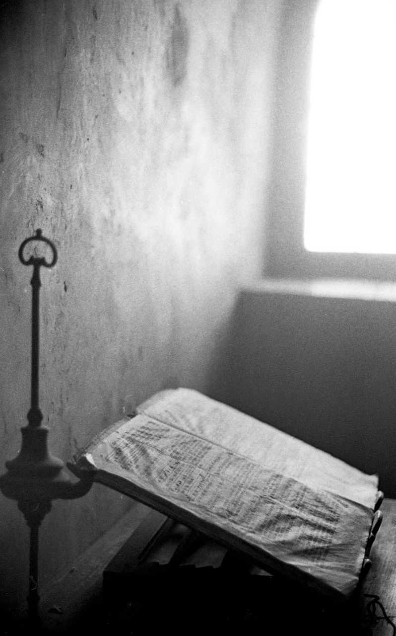 CLOSE-UP OF OPEN BOOK ON TABLE BY WALL