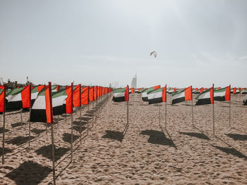 Uae flags on beach against sky, kite and burj al arab