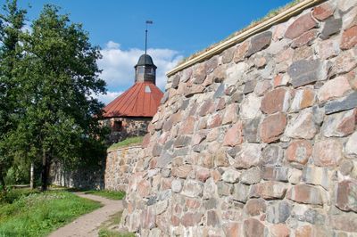 Brick wall by building against sky