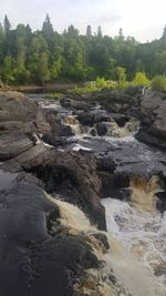 Scenic view of waterfall in forest against sky