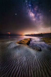 Scenic view of sea against sky and milkyway at night