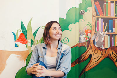 Smiling woman sitting against painted wall