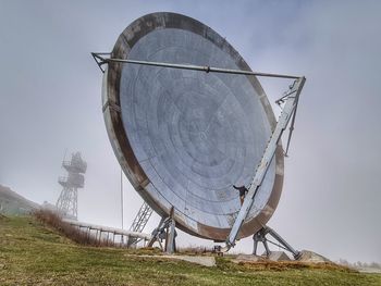 Low angle view of radar on field against sky