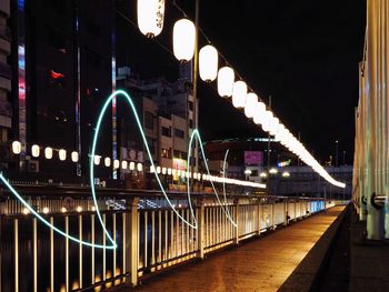 Illuminated bridge over river in city at night