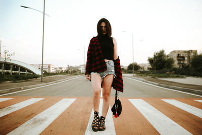 Full length of fashionable young woman on zebra crossing in city