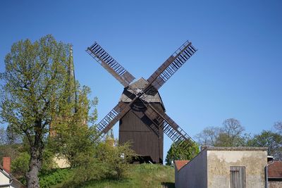 Low angle view of traditional windmill against clear blue sky