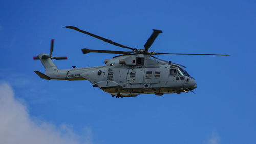 Low angle view of helicopter flying against blue sky