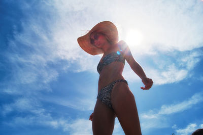 Low angle view of woman in bikini standing against sky