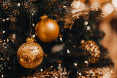 Golden christmas balls hanging on the christmas tree. bokeh magic effect. festive winter holiday