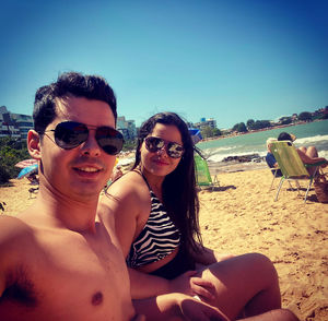 Portrait of smiling young couple sitting on beach