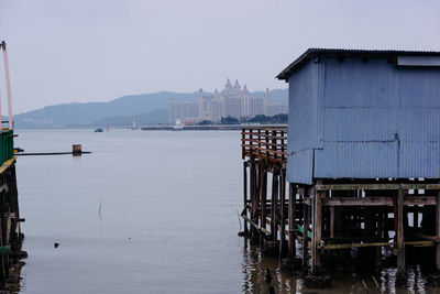 Wooden posts on pier over lake against sky