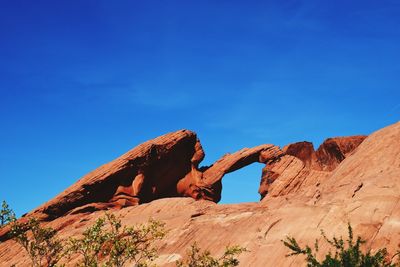 Low angle view of rock formation against clear blue sky