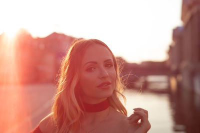 Portrait of a beautiful young woman against sky during sunset