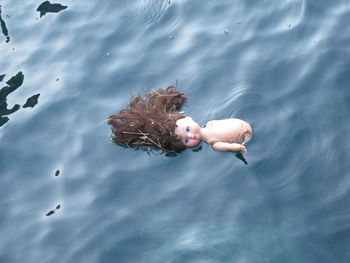 High angle view of broken doll floating on water