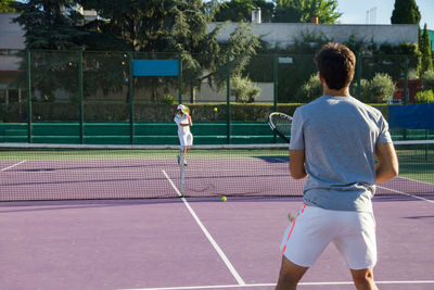 Male friends playing tennis on court