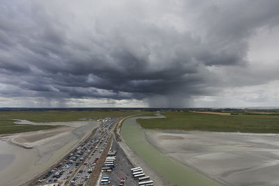 Road amidst landscape against storm clouds