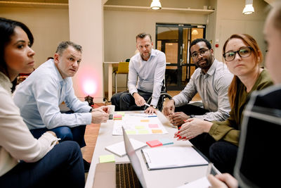 Sales executives looking at businesswoman during meeting in office