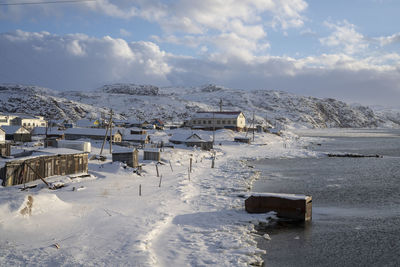 Buildings by sea against sky during winter